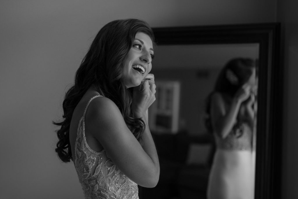 bride putting earrings on and smiling