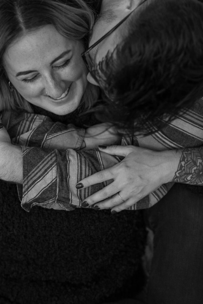 man hugging woman from behind and kissing her cheek