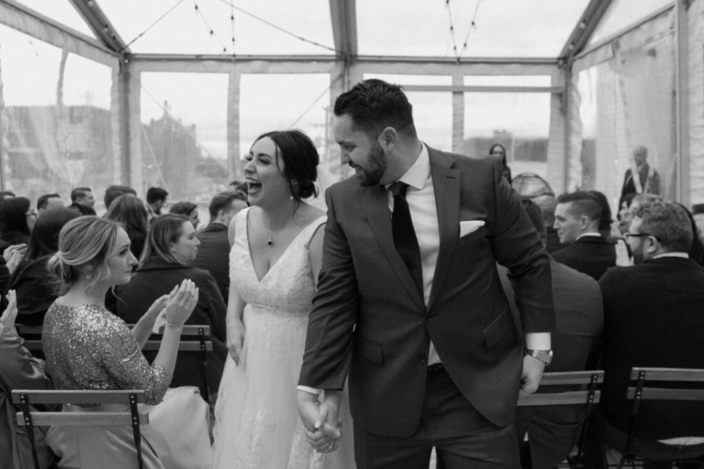 bride and groom walking up the aisle smiling and holding hands