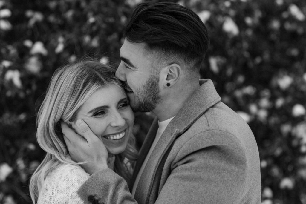 man gently holding woman's face and kissing her forehead