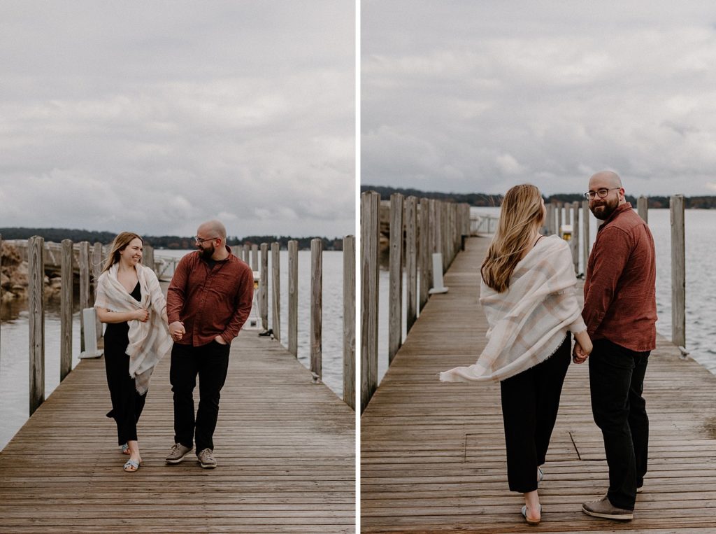 couple holding hands and smiling as they walk on a pier