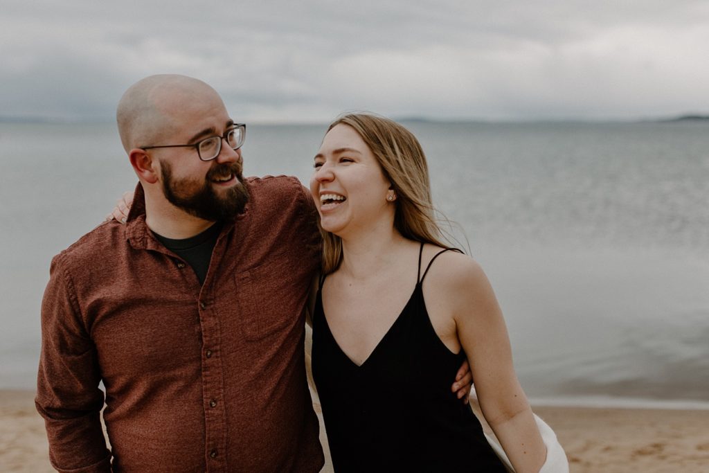 couple walking along the beach with their arms around each other