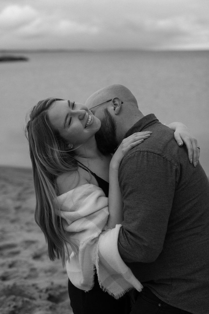 man kissing woman's neck as she smiles
