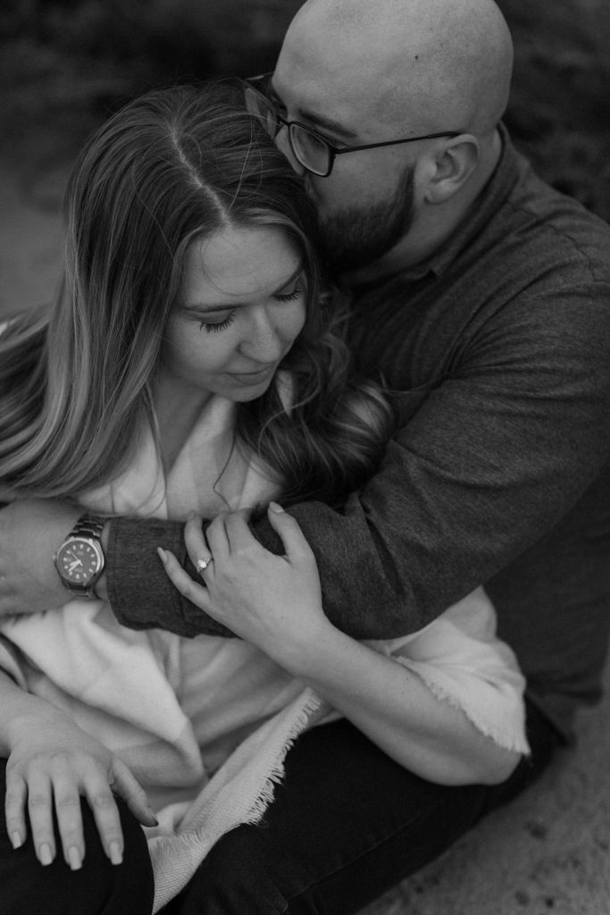 man with his arms around a woman kissing her head