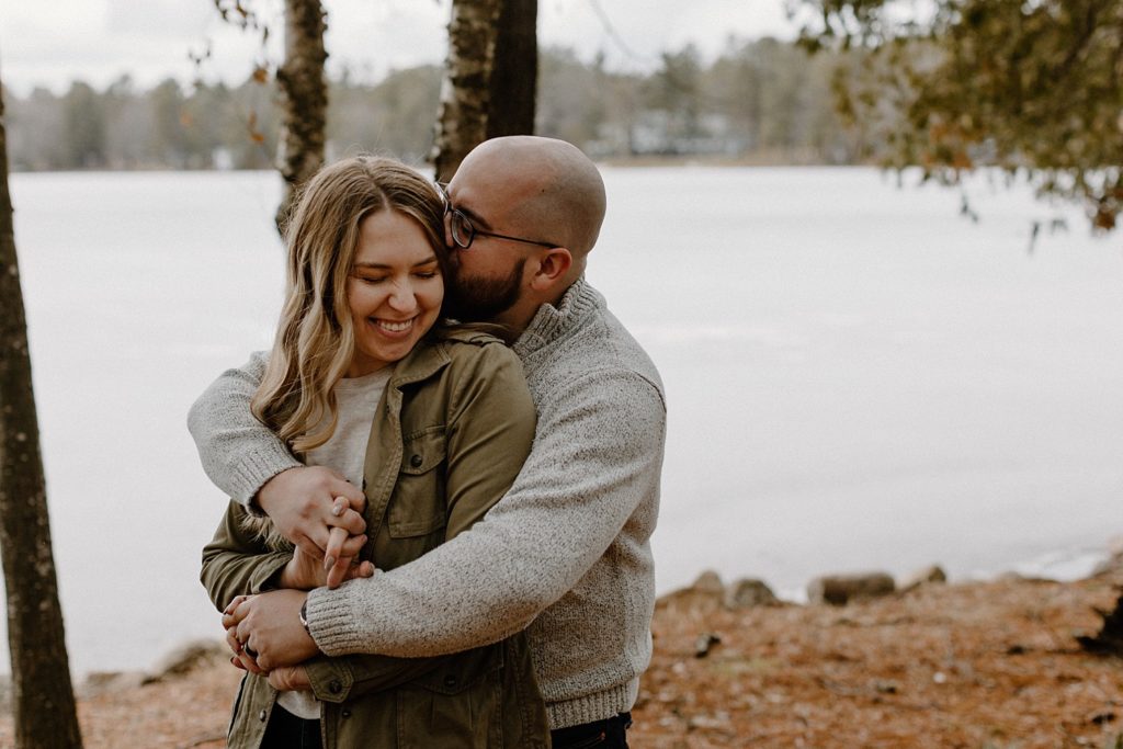 man hugging a woman from behind and kissing her as they hold hands