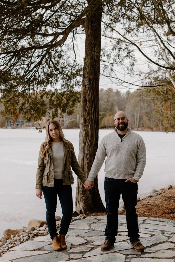couple holding hands and standing in front of the water