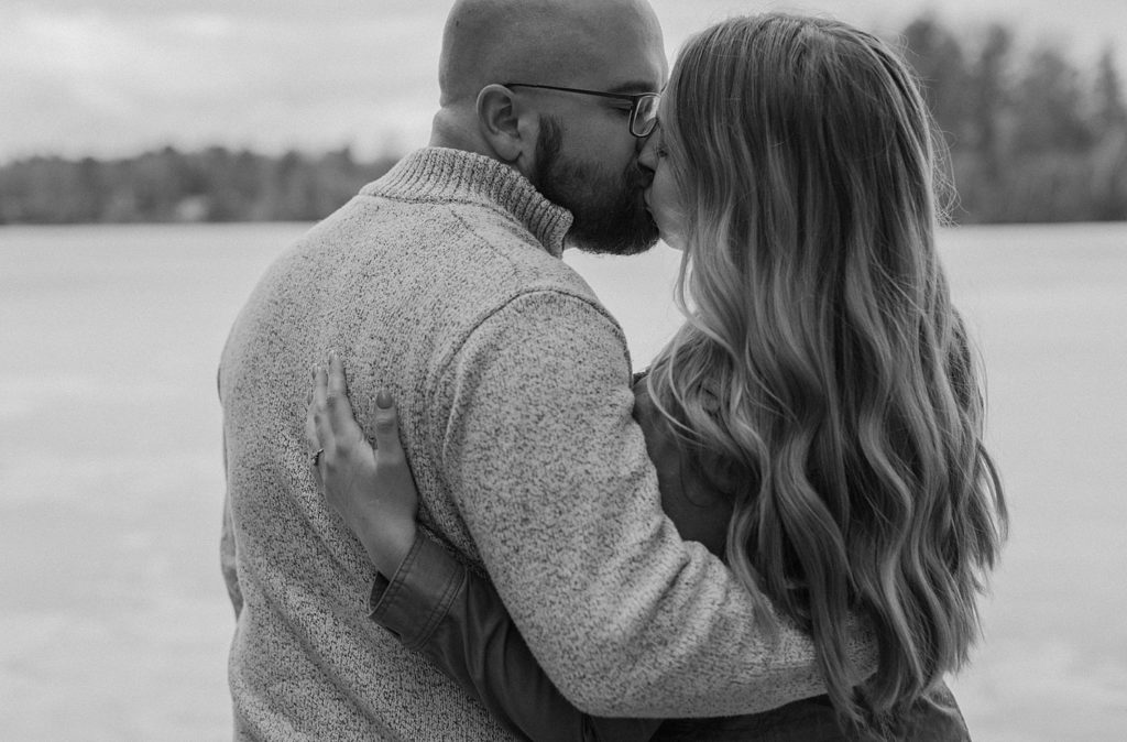 couple kissing while standing in front of the water