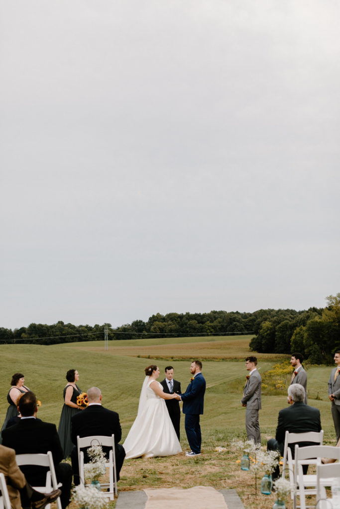 view of bride and groom from the end of the aisle as they say their vows