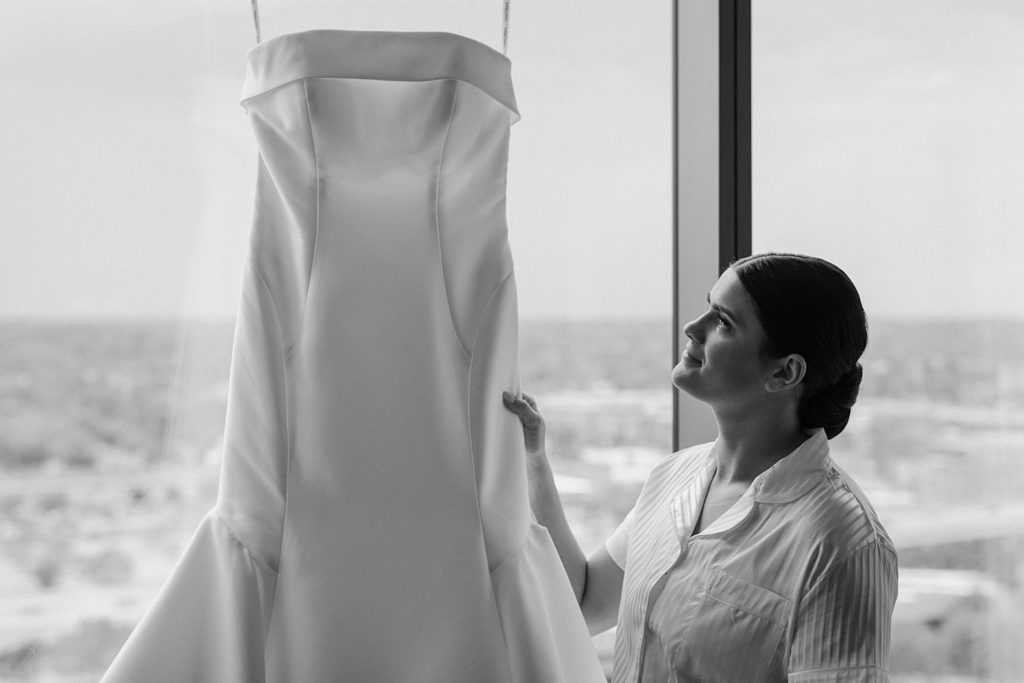 bride looking a wedding dress as it is handing up 