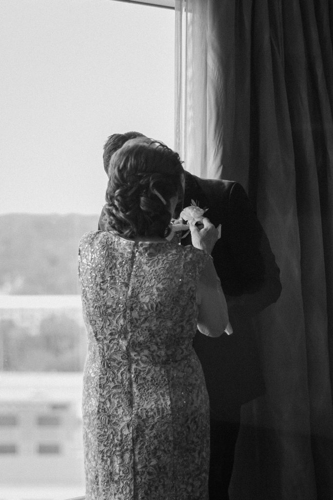 mother helping groom put on his boutonniere 