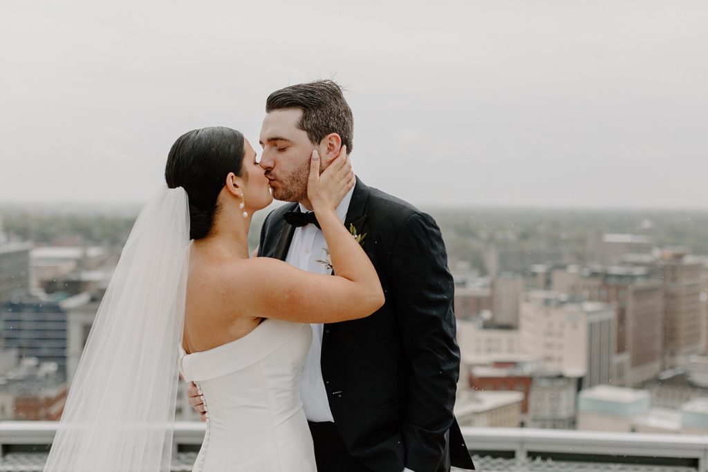 bride and groom kissing while her hands are on his face 