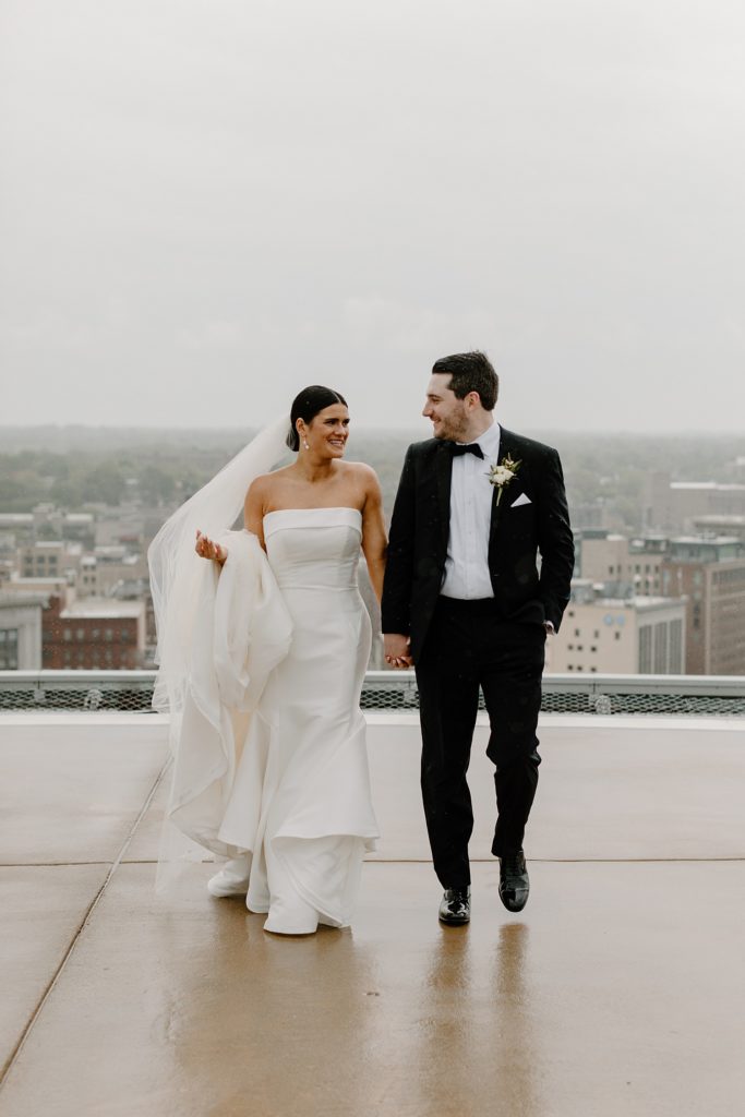 couple holding hands and walking on rooftop 