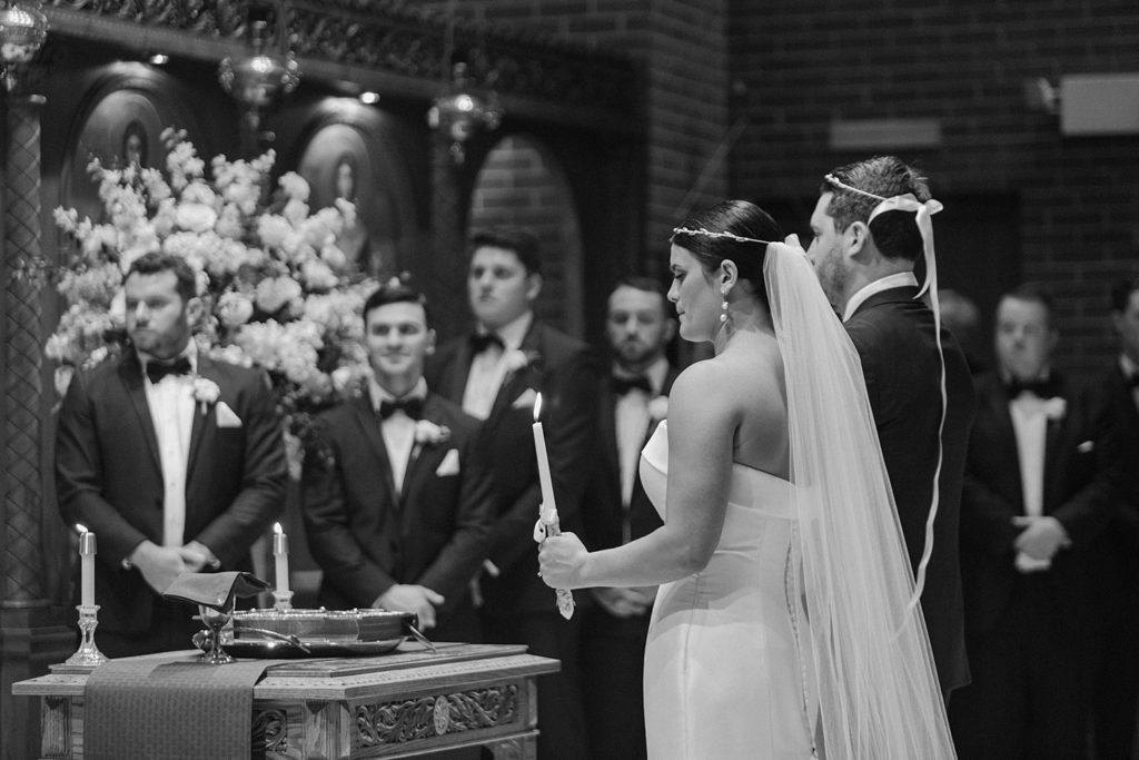 couple standing on the altar holding candles 
