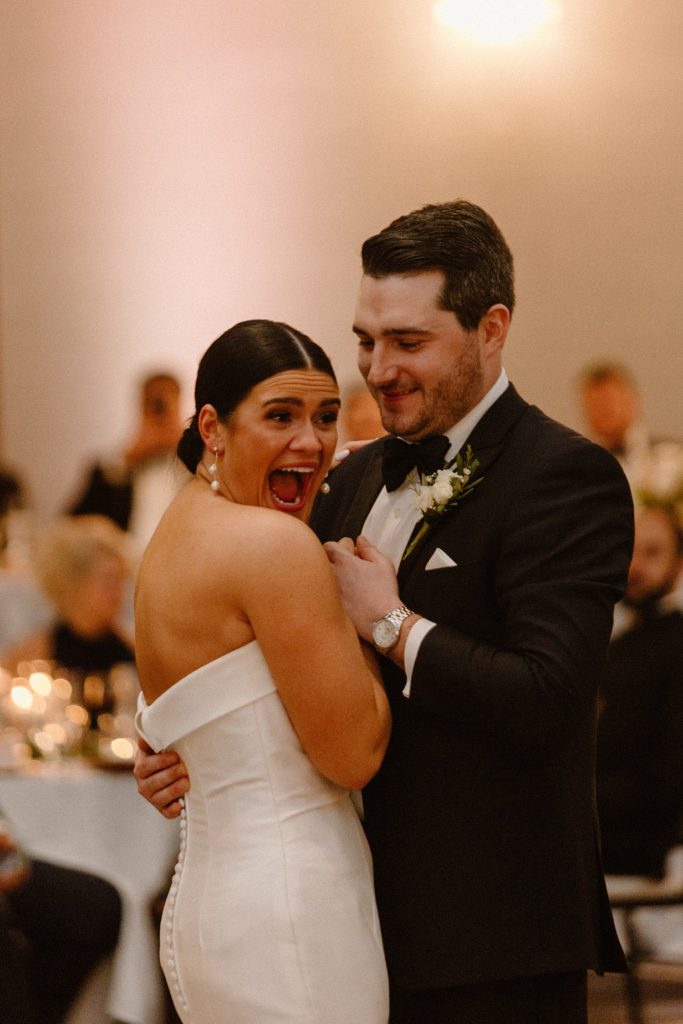 bride smiling while dancing with groom 