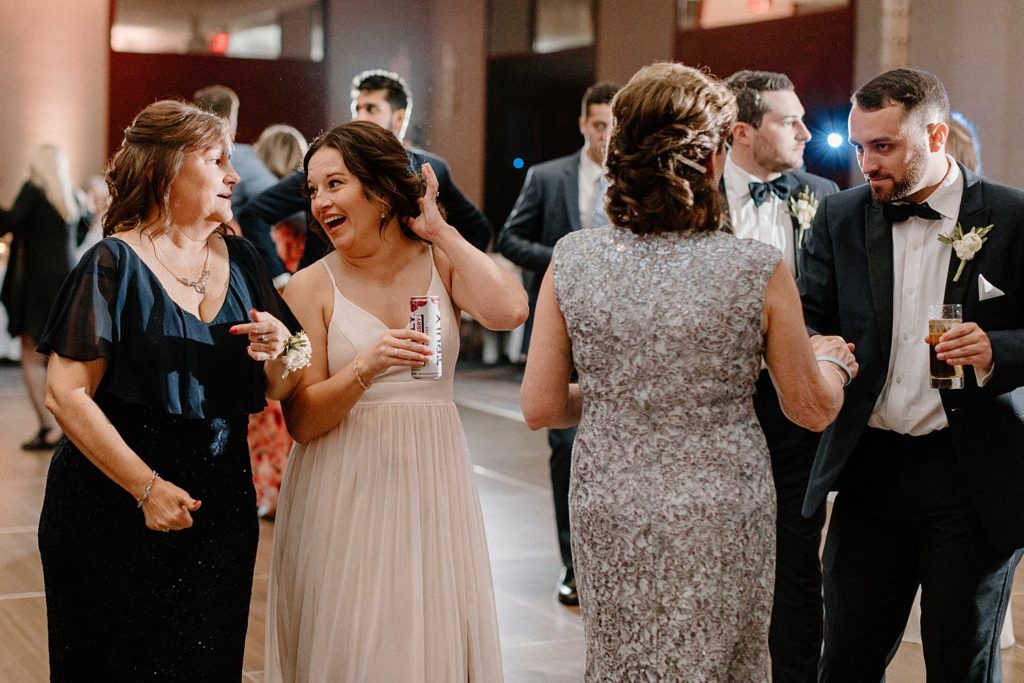 guests holding drinks and talking on the dance floor 