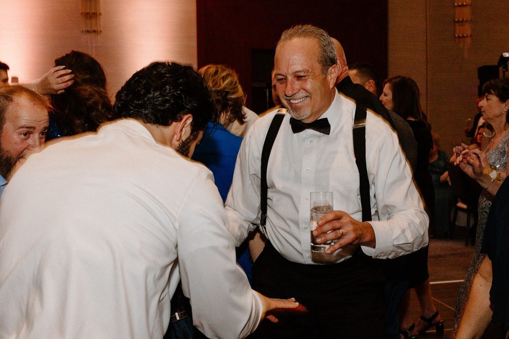wedding guests holding drinks and smiling on the dance floor 