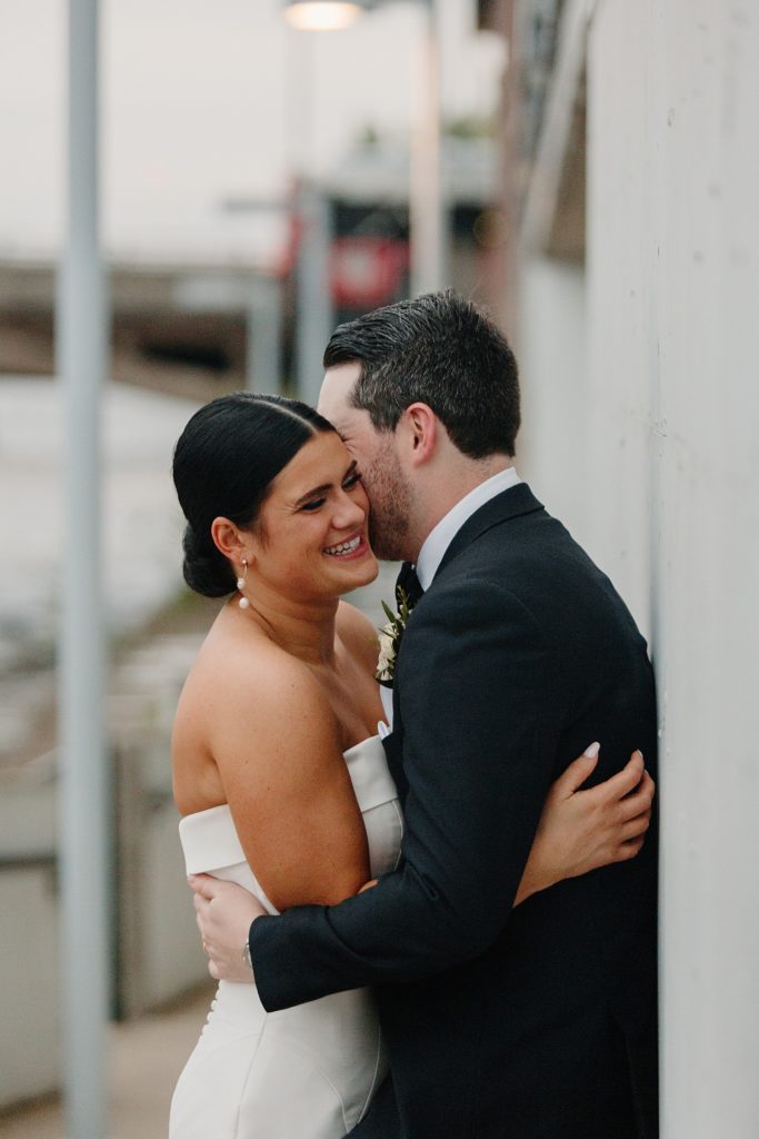 bride and groom hugging while the bride smiles 