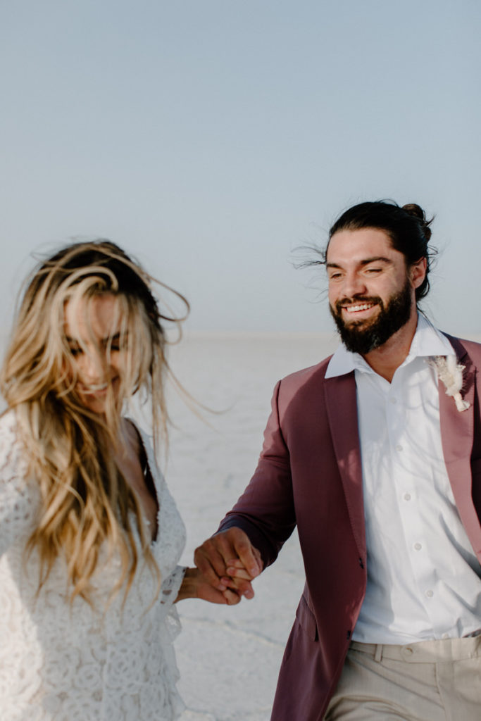 groom holding brides hand and smiling as she looks away