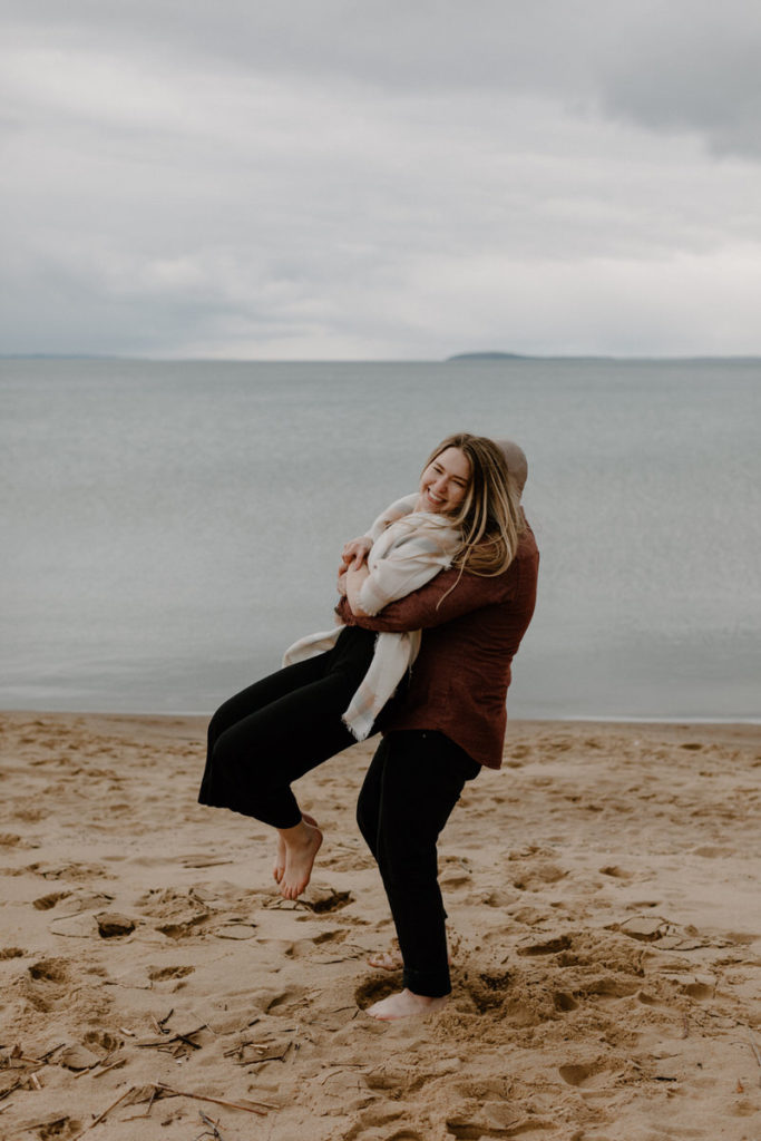 man with his arms around a woman holding her up on the water's edge