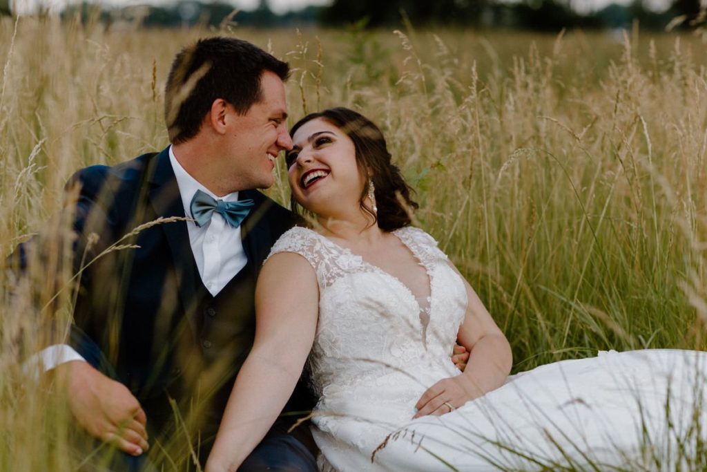 couple sitting together in a large field smiling at each other