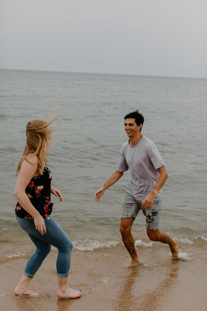couple playing and chasing each other on the edge of the water