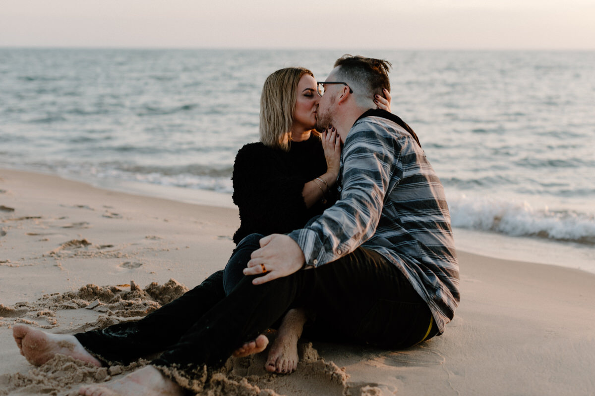 couple sitting on the water's edge kissing