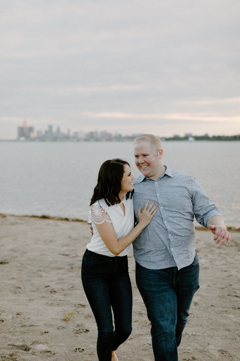 couple with their arms around each other walking down the beach