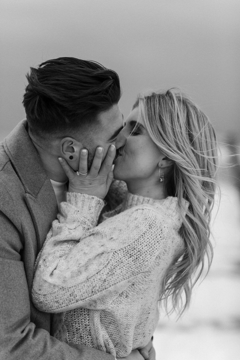 couple hugging each other and kissing on a snowy beach