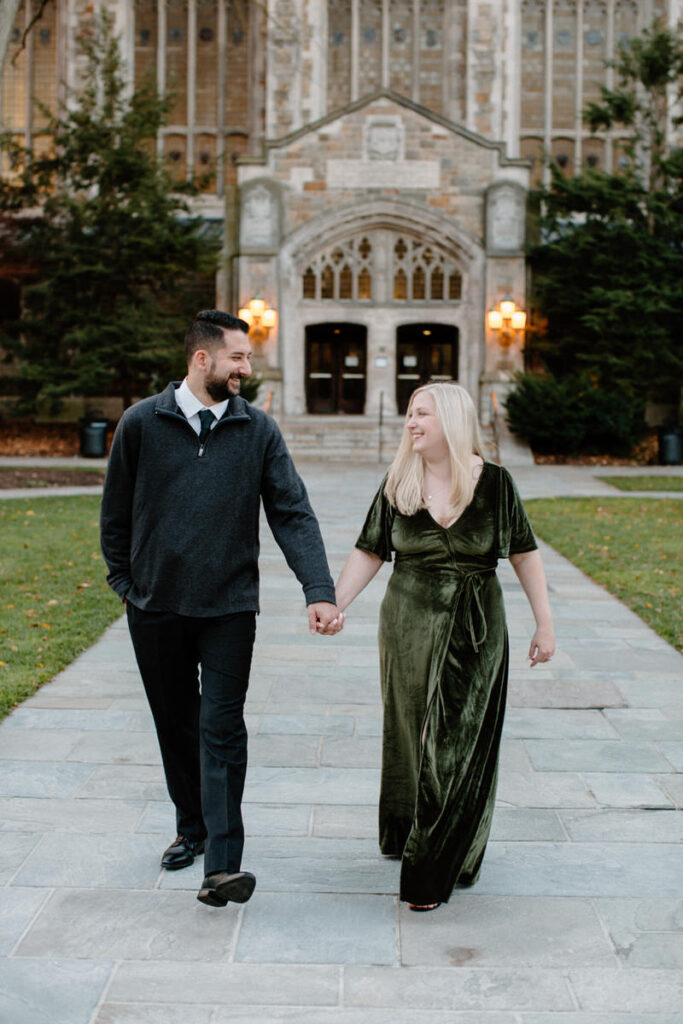 couple walking on a path in front of a large building holding hands