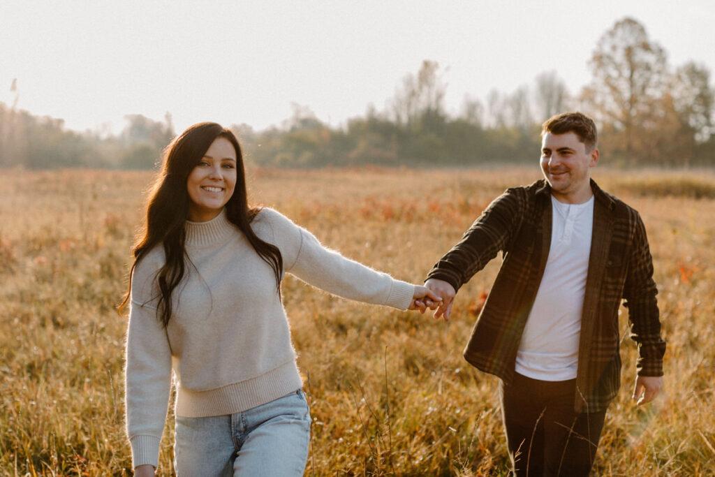 couple walking hand in hand in a large field