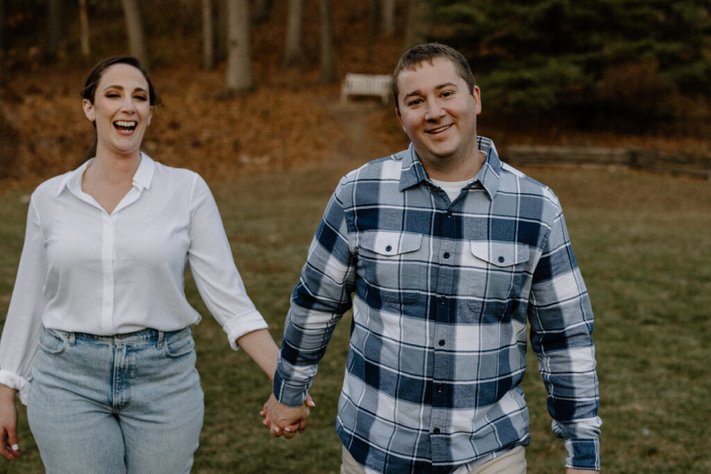 Couple smiling as one looks at the other from behind while holding hands