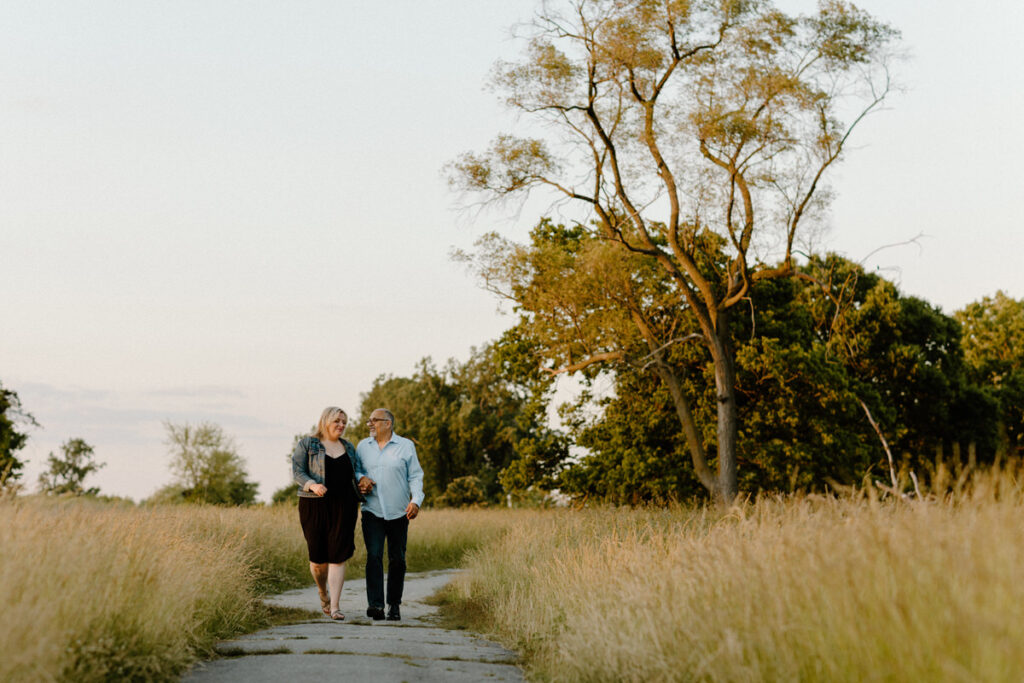 couple walking together along a walkway between two fields of grass