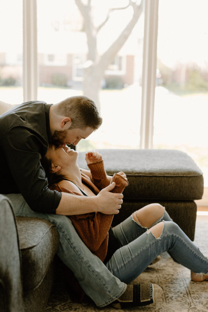man sitting on a couch leaning over a woman who is sitting on the floor below him
