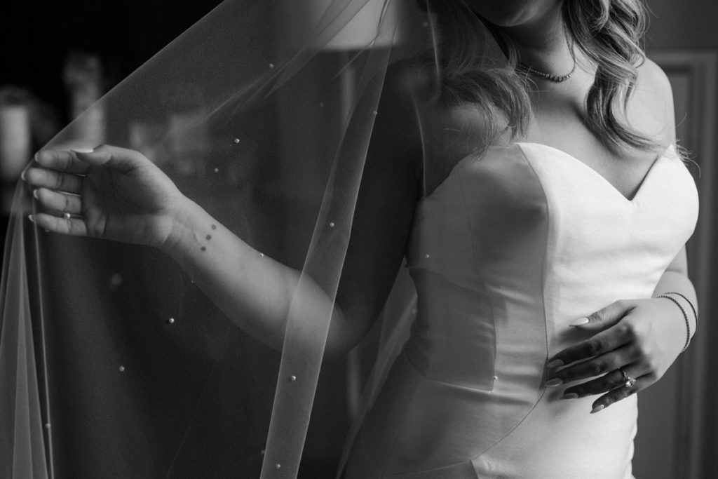 black and white close up view of a bride's vail held out to the side of her dress