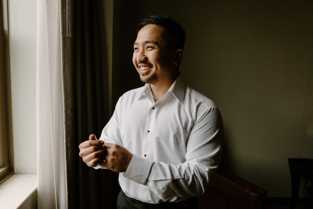 groom smiling as he adjusts his shirt sleeve