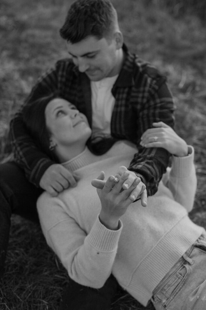 woman lying in a man's lap looking up at him while they hold hands